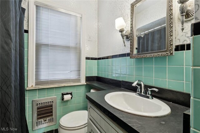 full bath featuring wainscoting, vanity, toilet, tile walls, and heating unit