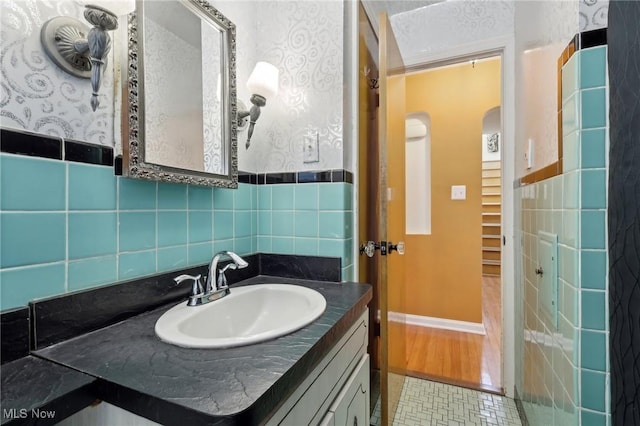 bathroom featuring vanity, baseboards, and wallpapered walls