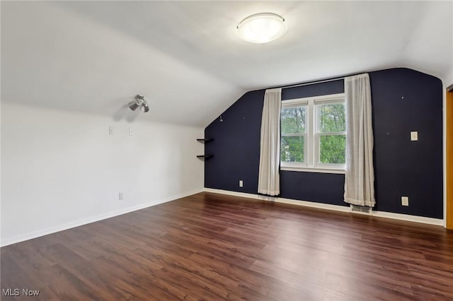 additional living space with baseboards, vaulted ceiling, and wood finished floors