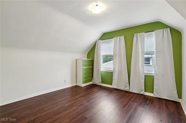additional living space featuring baseboards, vaulted ceiling, and wood finished floors