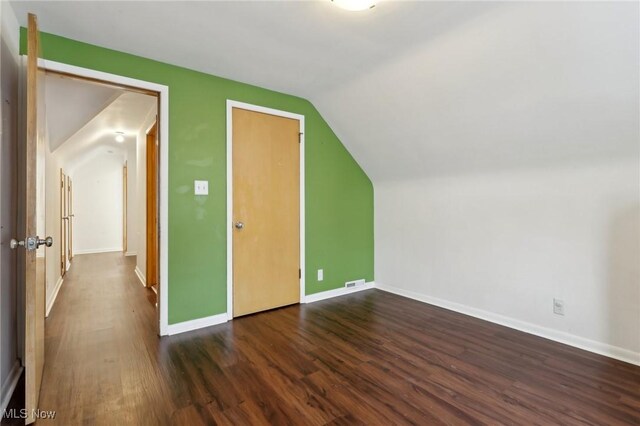 bonus room featuring baseboards, vaulted ceiling, dark wood finished floors, and visible vents