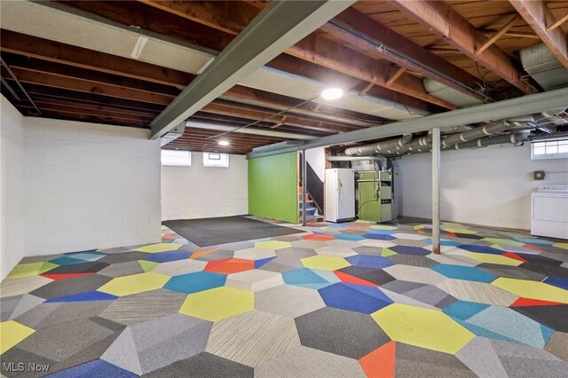 basement featuring freestanding refrigerator, washer / dryer, heating unit, stairway, and concrete block wall