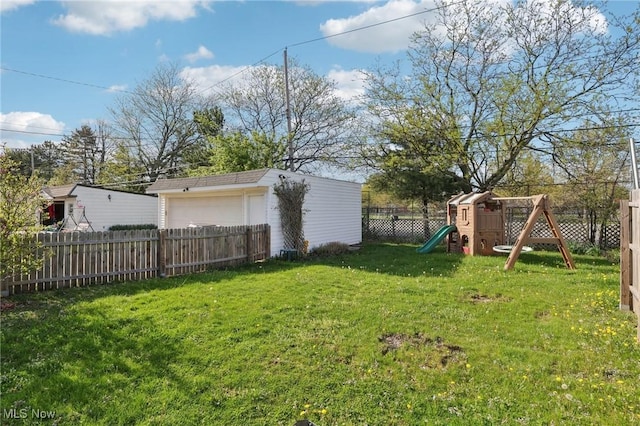 view of yard featuring a playground, a detached garage, an outdoor structure, and a fenced backyard