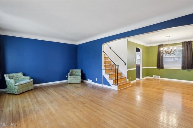 unfurnished room featuring visible vents, arched walkways, wood-type flooring, a notable chandelier, and stairs
