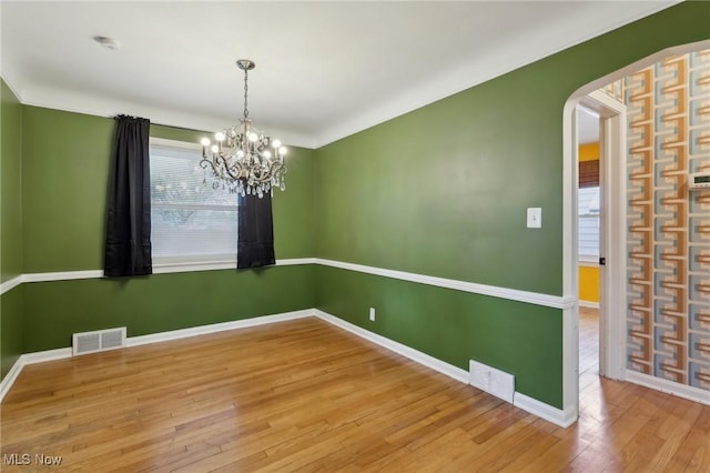 spare room with baseboards, visible vents, an inviting chandelier, and hardwood / wood-style flooring