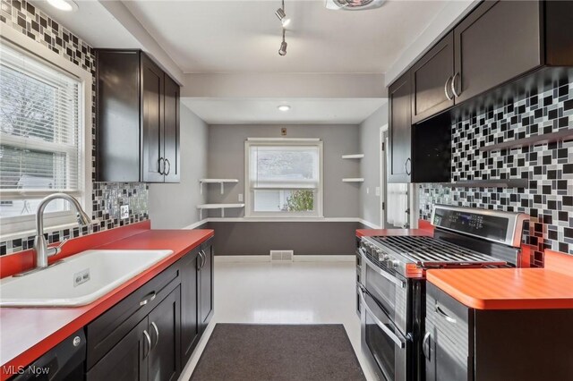kitchen with backsplash, visible vents, range with two ovens, a sink, and light countertops