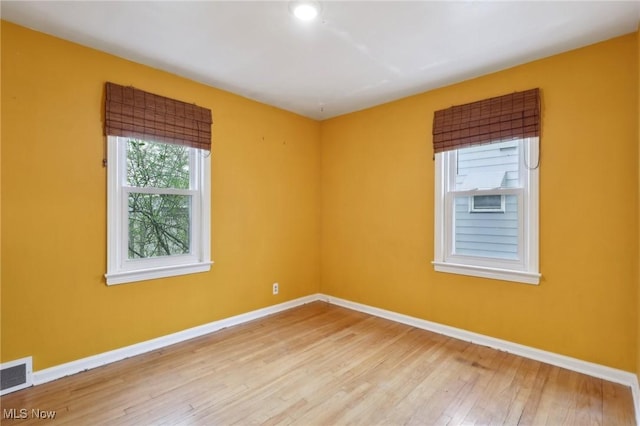 empty room with baseboards, visible vents, and light wood-style flooring