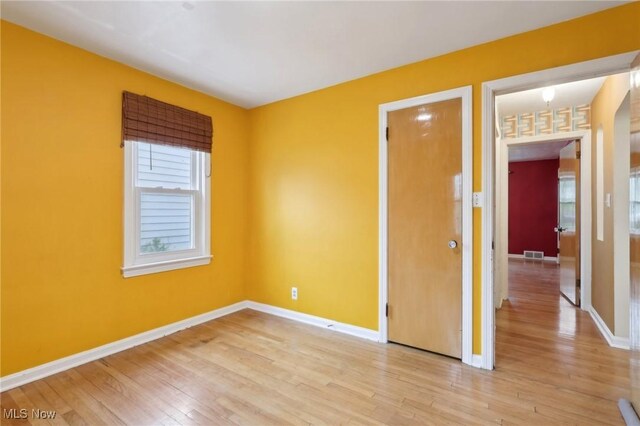 spare room featuring baseboards, light wood-style flooring, and visible vents