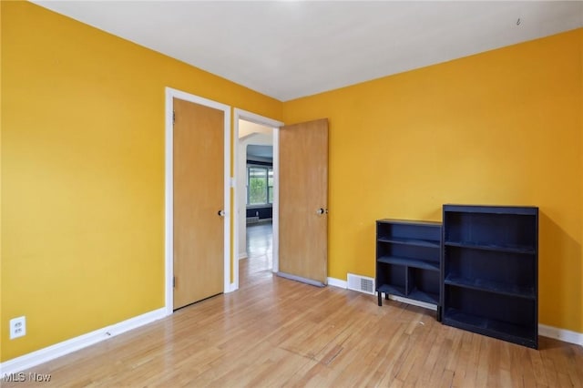 spare room with wood-type flooring, baseboards, and visible vents