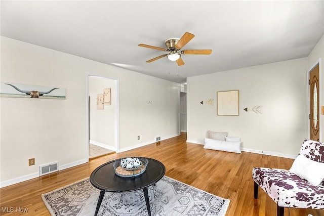 living area with baseboards, ceiling fan, visible vents, and wood finished floors