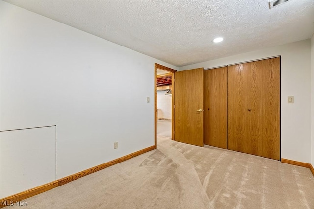 unfurnished bedroom with a closet, baseboards, recessed lighting, a textured ceiling, and carpet