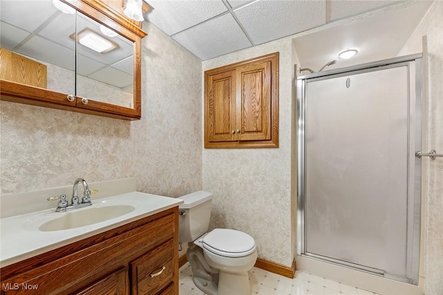 bathroom with vanity, toilet, a paneled ceiling, tile patterned floors, and a shower stall