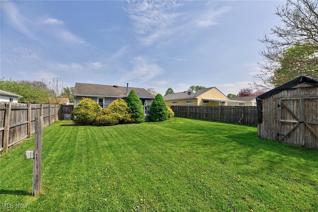 view of yard with an outdoor structure, a fenced backyard, and a storage unit
