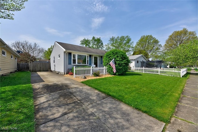 view of front of home featuring concrete driveway, fence private yard, and a front lawn