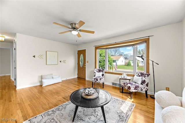 living room with a ceiling fan, baseboards, and wood finished floors