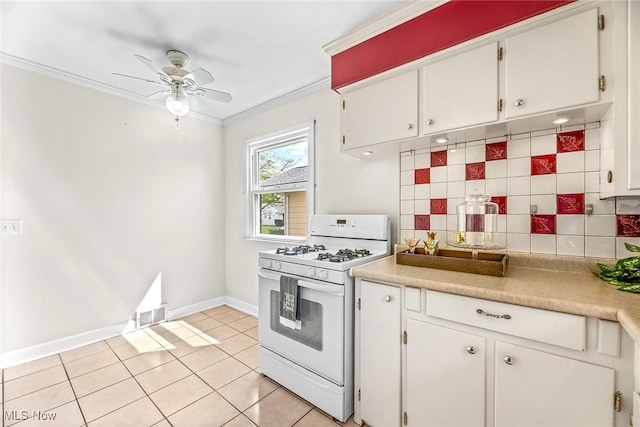 kitchen with crown molding, light tile patterned flooring, ceiling fan, tasteful backsplash, and white gas range oven