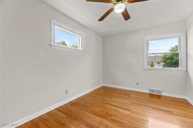 empty room with baseboards, visible vents, a wealth of natural light, and light wood-style floors