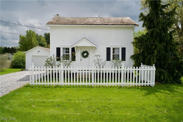 view of front of property featuring an outdoor structure, a garage, a fenced front yard, and gravel driveway
