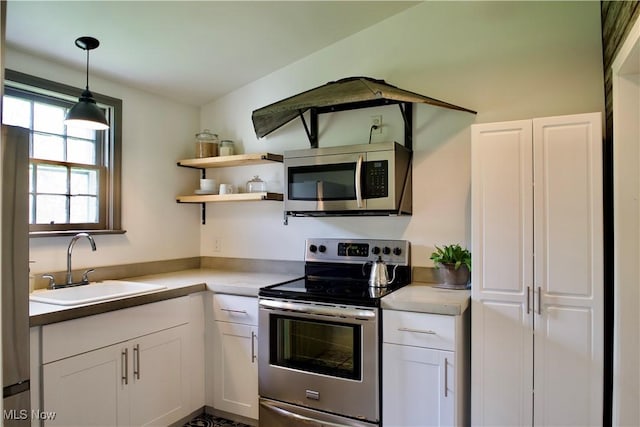 kitchen with white cabinets, stainless steel appliances, a sink, and light countertops
