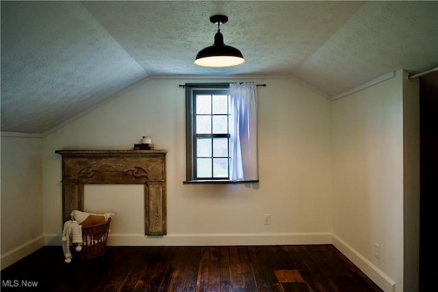 additional living space with baseboards, dark wood-style floors, a textured ceiling, and lofted ceiling