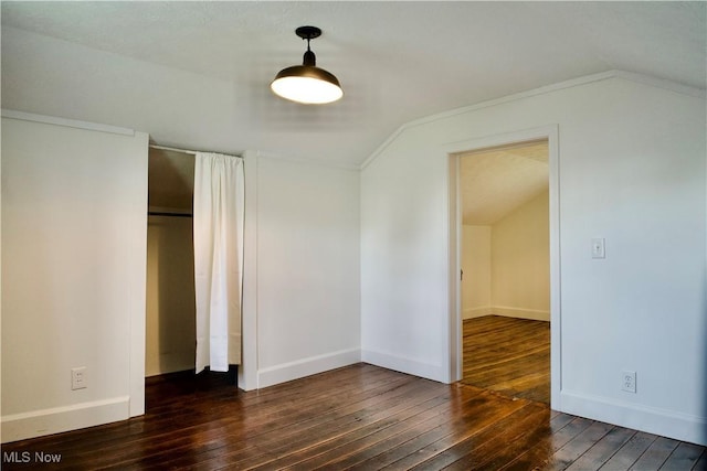 unfurnished bedroom featuring a closet, baseboards, lofted ceiling, and hardwood / wood-style floors