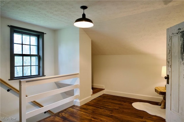 additional living space featuring a textured ceiling, dark wood-style floors, and baseboards