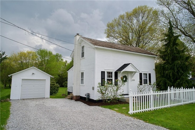 view of front of house featuring an outdoor structure, fence, a chimney, driveway, and a detached garage