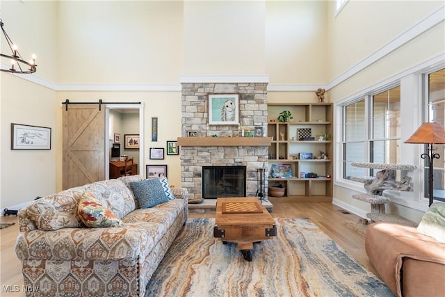46748 New London Eastern Rd, New London, OH 44851 - living area featuring a fireplace, a barn door, wood finished floors, a chandelier, and a high ceiling