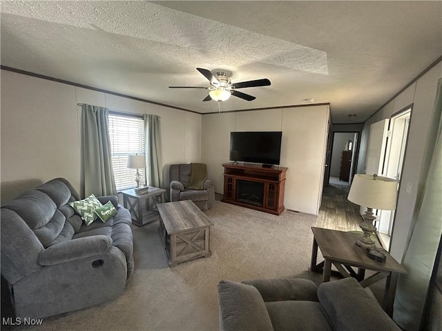carpeted living area with a ceiling fan, a textured ceiling, and a fireplace
