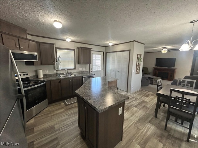 kitchen featuring dark brown cabinetry, a sink, stainless steel appliances, dark wood-type flooring, and a kitchen island