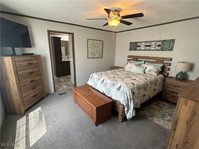carpeted bedroom with crown molding, a textured ceiling, and ensuite bathroom