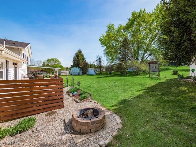 view of yard featuring a storage shed, an outdoor structure, and an outdoor fire pit
