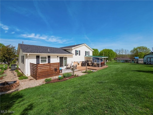 rear view of property with a shed, cooling unit, a patio area, a yard, and a fire pit