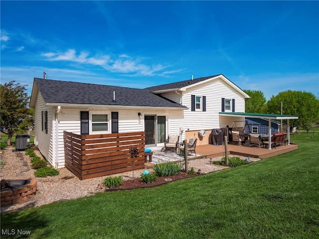 back of property featuring a lawn, a deck, a shingled roof, central AC, and a fire pit