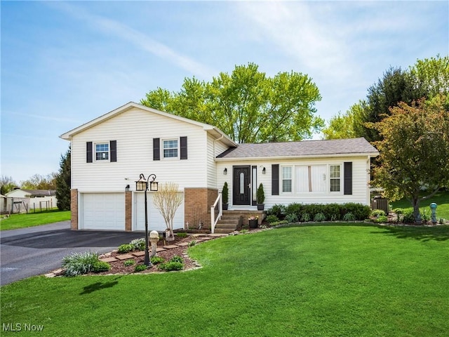 split level home with driveway, a front yard, a garage, central air condition unit, and brick siding