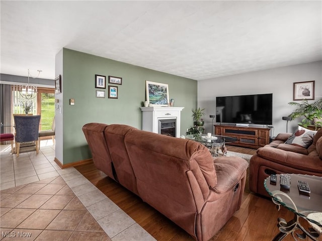 living area featuring an inviting chandelier, baseboards, light tile patterned flooring, and a fireplace