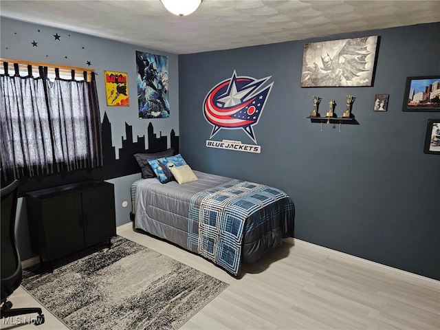 bedroom with baseboards and wood finished floors