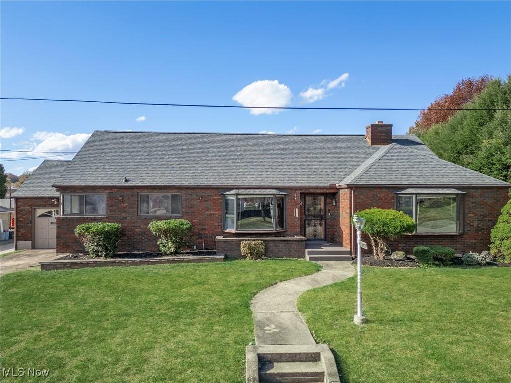 1307 Plum St, Parkersburg, WV 26104 - view of front of house with brick siding, a shingled roof, and a front lawn