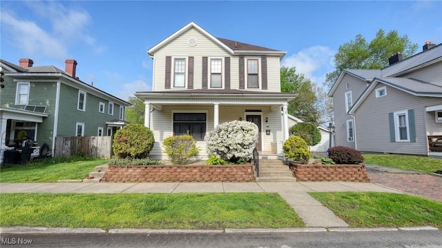 traditional home with a porch, fence, and a front yard