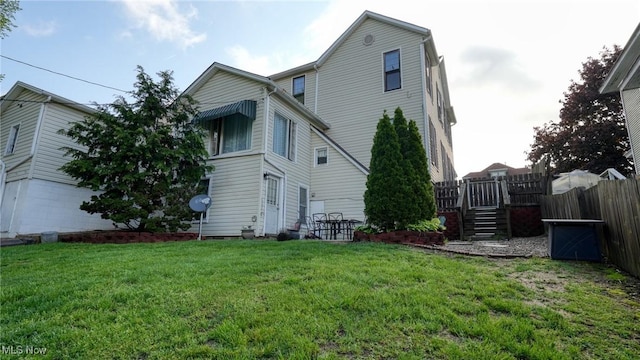 back of house featuring a lawn and fence