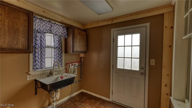 doorway to outside with a sink and baseboards