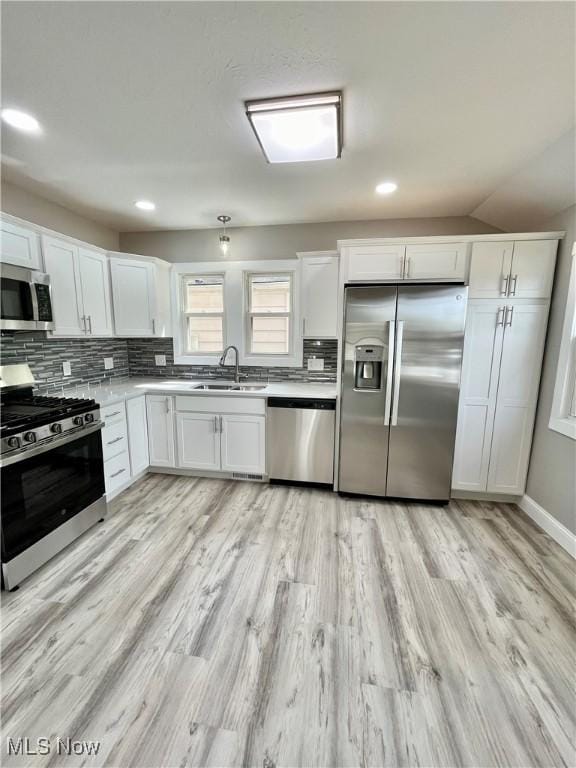 kitchen featuring white cabinets, appliances with stainless steel finishes, a sink, and light wood finished floors