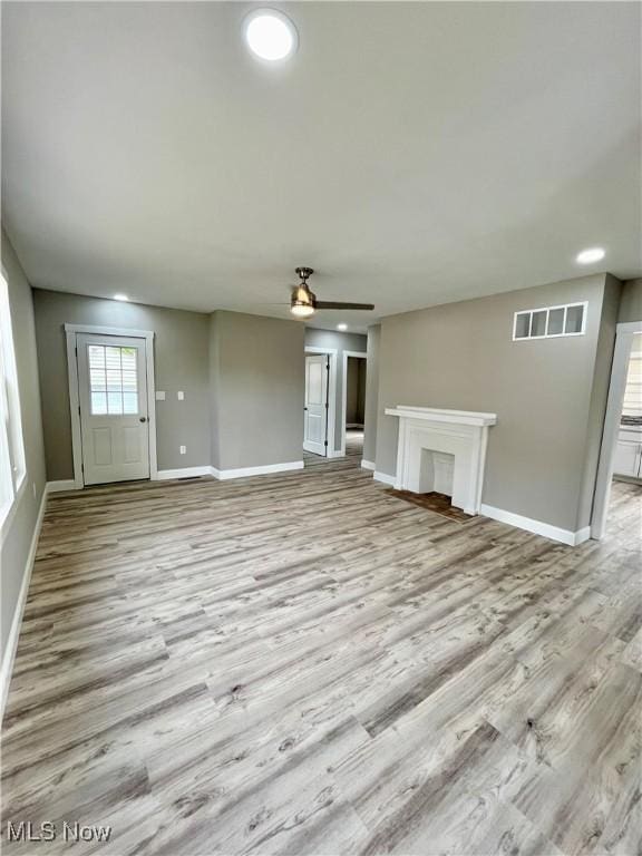unfurnished living room with baseboards, a ceiling fan, wood finished floors, and visible vents
