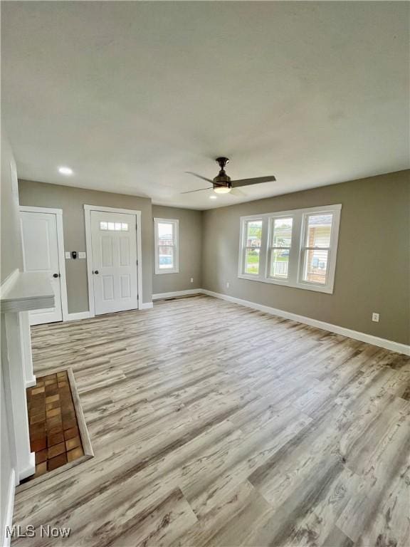 unfurnished living room with baseboards, light wood-style flooring, and ceiling fan