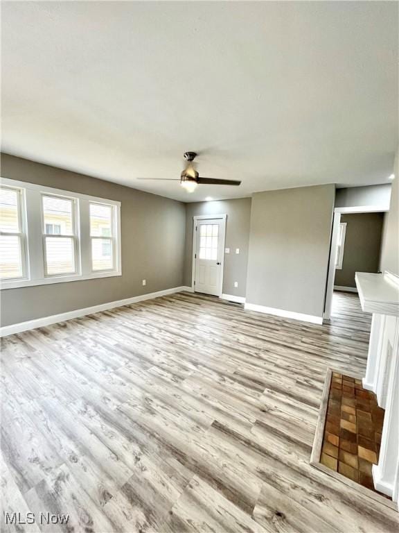 unfurnished living room featuring baseboards, ceiling fan, and wood finished floors