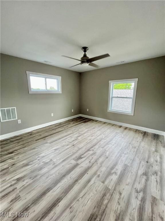 unfurnished room featuring visible vents, baseboards, wood finished floors, and a wealth of natural light