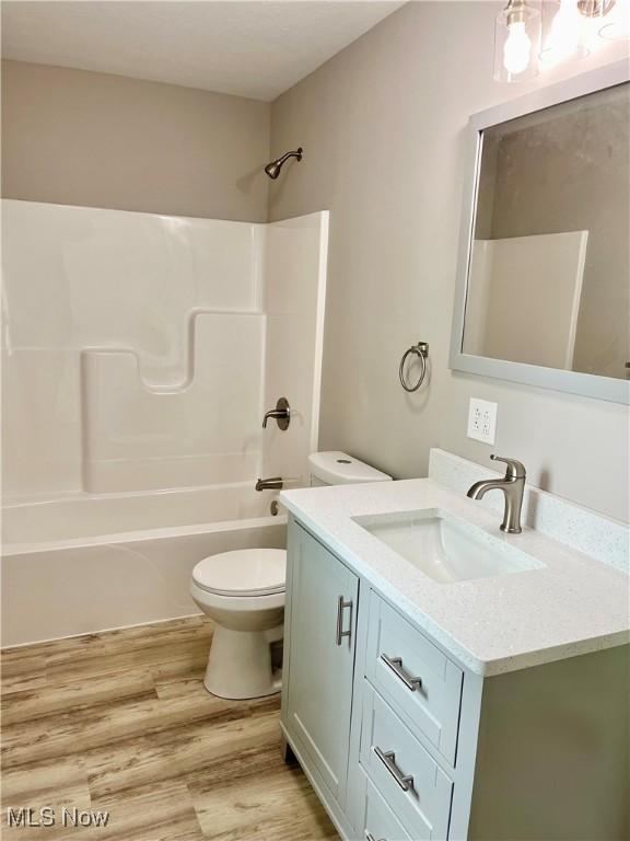 full bathroom with toilet, shower / washtub combination, wood finished floors, and vanity