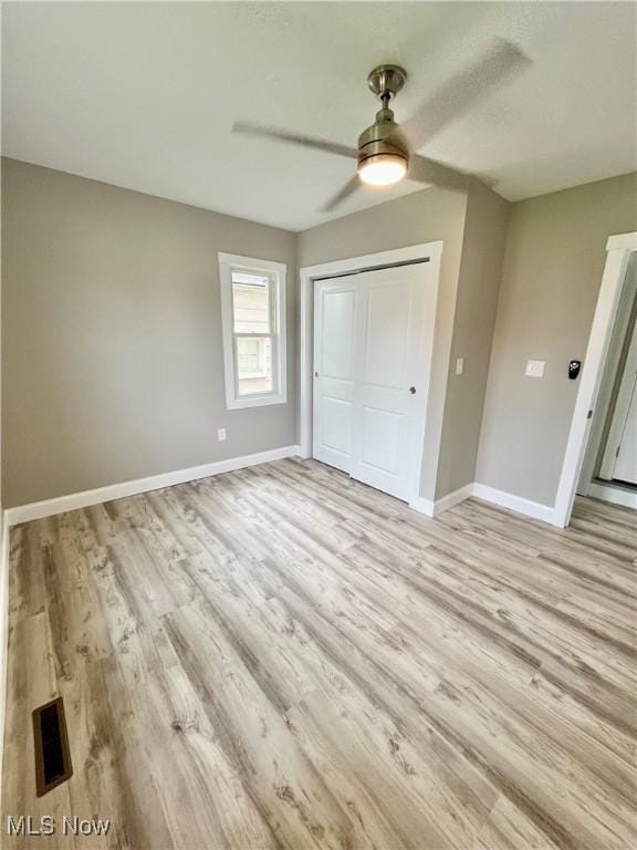 unfurnished bedroom featuring visible vents, a closet, baseboards, ceiling fan, and light wood finished floors