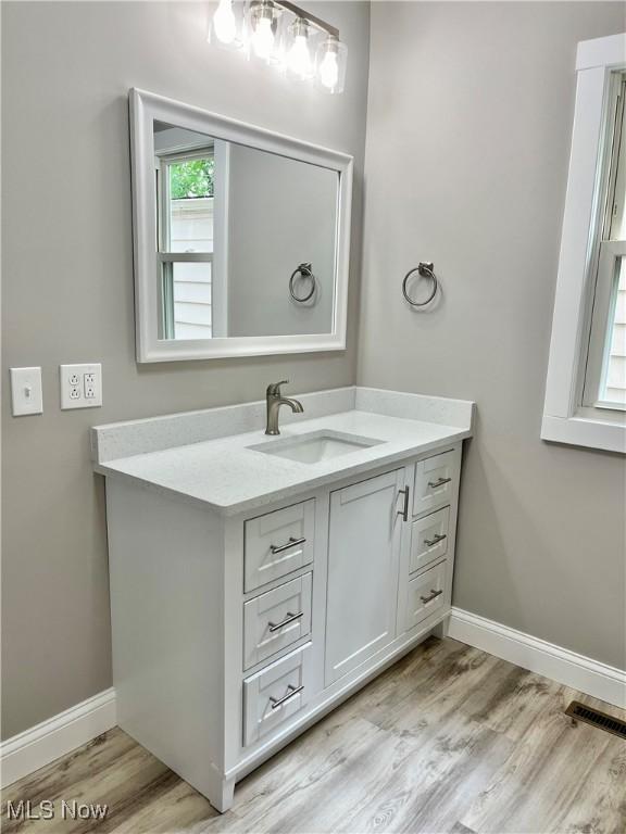 bathroom with baseboards, visible vents, wood finished floors, and vanity
