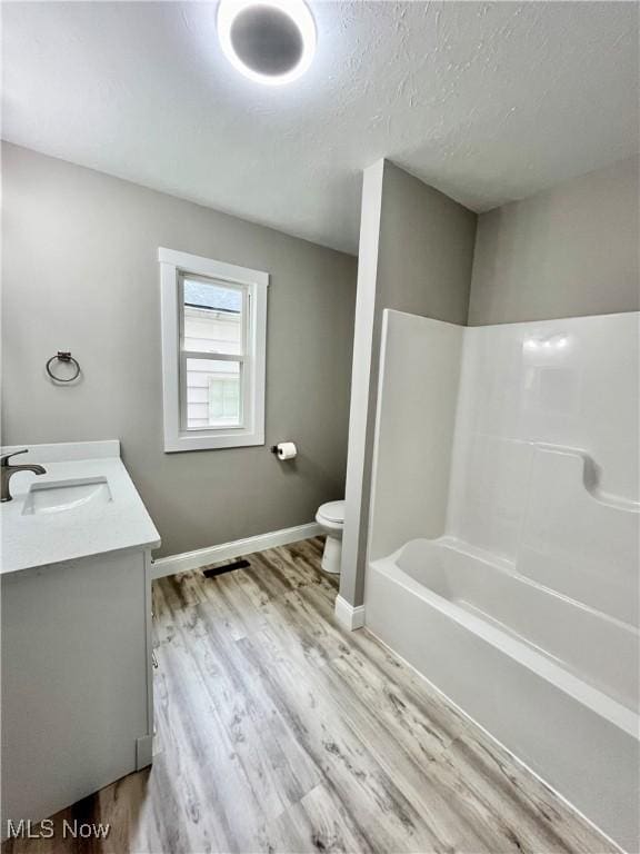 bathroom featuring vanity, toilet, a textured ceiling, baseboards, and wood finished floors